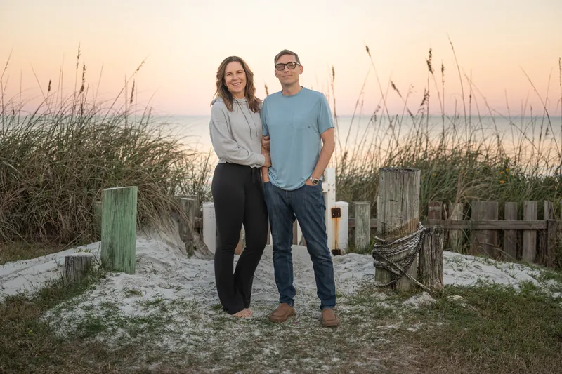 Rob and Jill Futrell walking a beach dune crossover at sunset