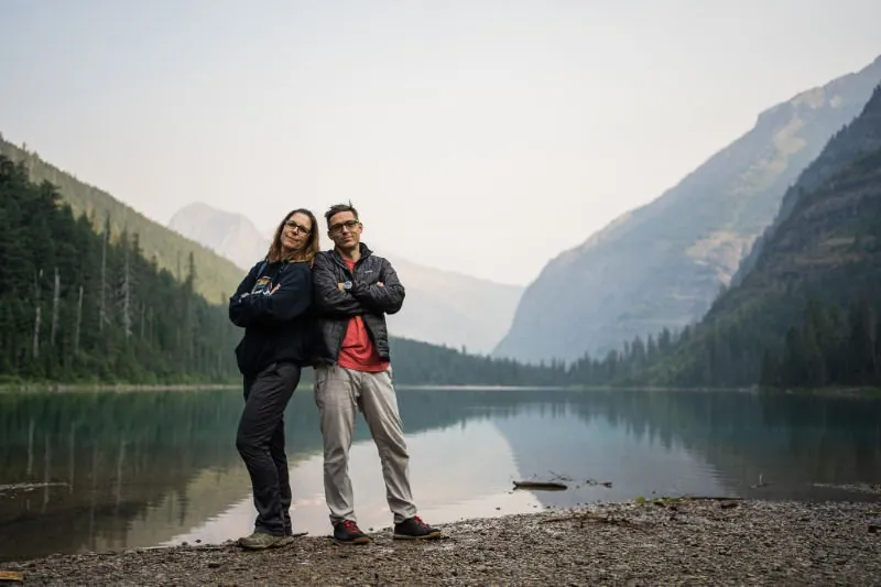 Rob and Jill Futrell standing back to back at a mountain lake
