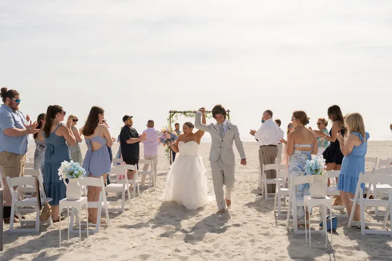 Couple celebrating beach elopement against stunning coastal sunset