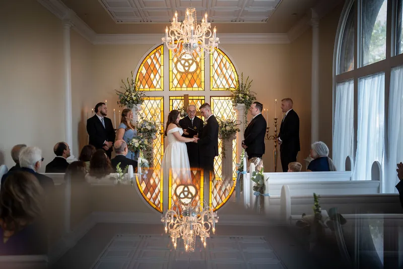 Chapel elopement ceremony with stained glass window and chandelier