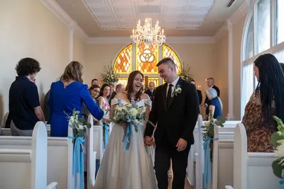 Newlyweds walking down chapel aisle with bride laughing joyfully