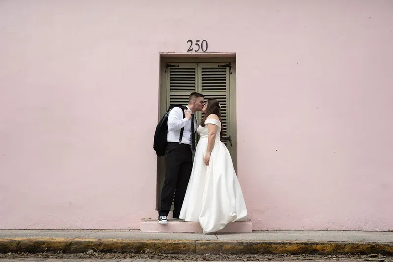 Couple kissing by pink wall with green shutters in historic district