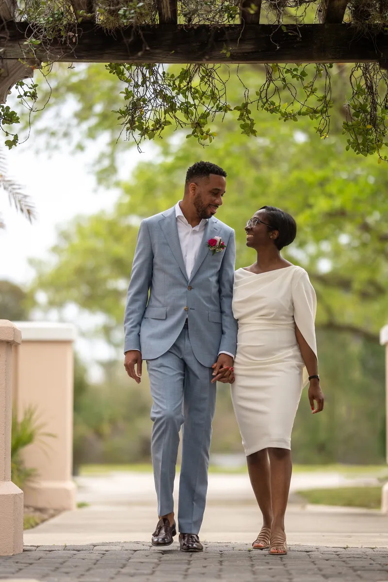 Couple walking hand in hand through garden pergola in St Augustine
