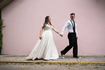 Couple walking hand in hand by pink wall in St Augustine