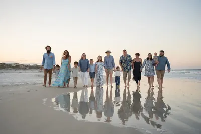 Extended family walking on the beach at sunset with reflections