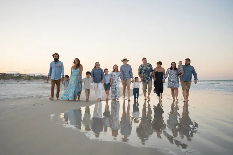 Extended family walking on the beach at sunset with reflections
