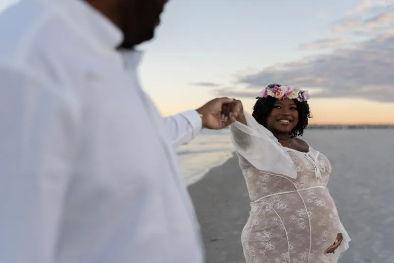 Joyful beach maternity moment at sunset