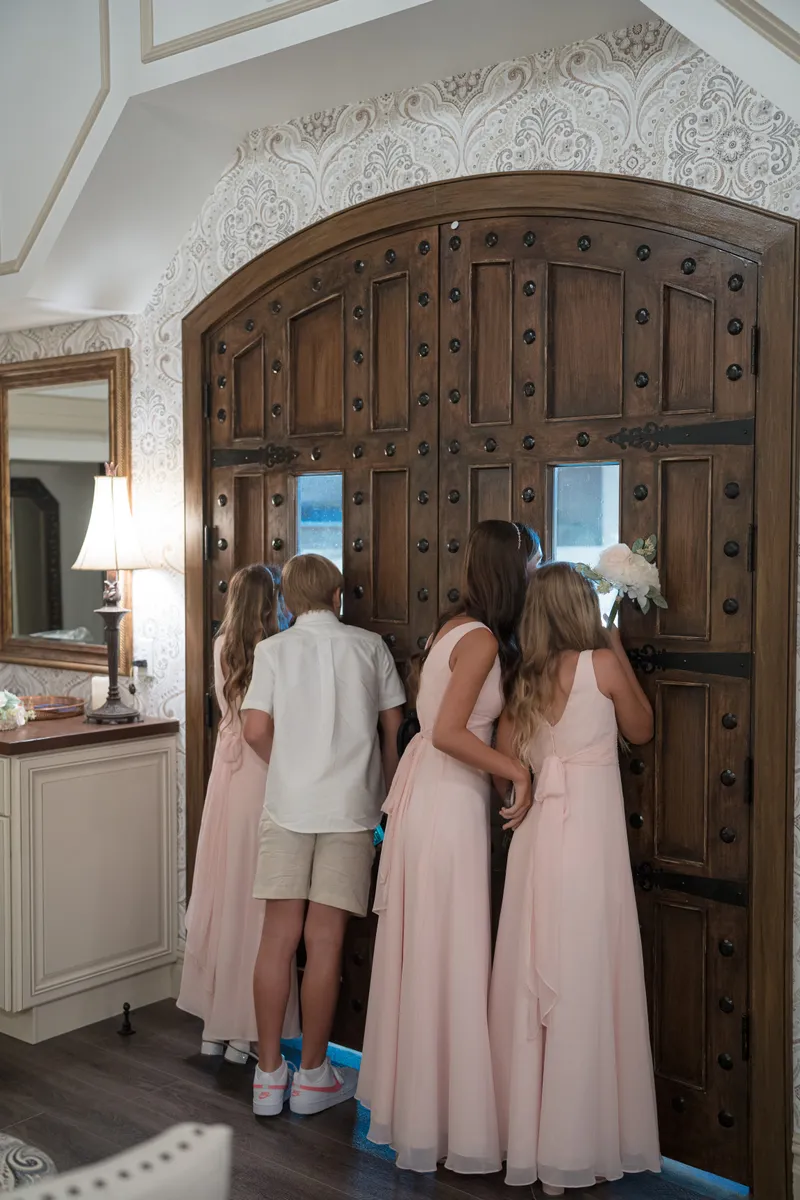 Children peek through wooden doors before ceremony