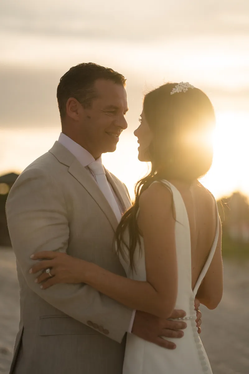 Jason lifts Abbey as her flowing dress billows around them on the beach at dusk, with moody clouds overhead.