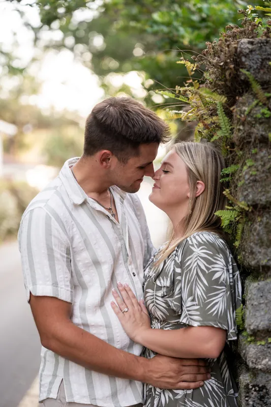 Gage and Abby lean against a moss-covered stone wall, sharing an intimate moment in Downtown St Augustine's historic