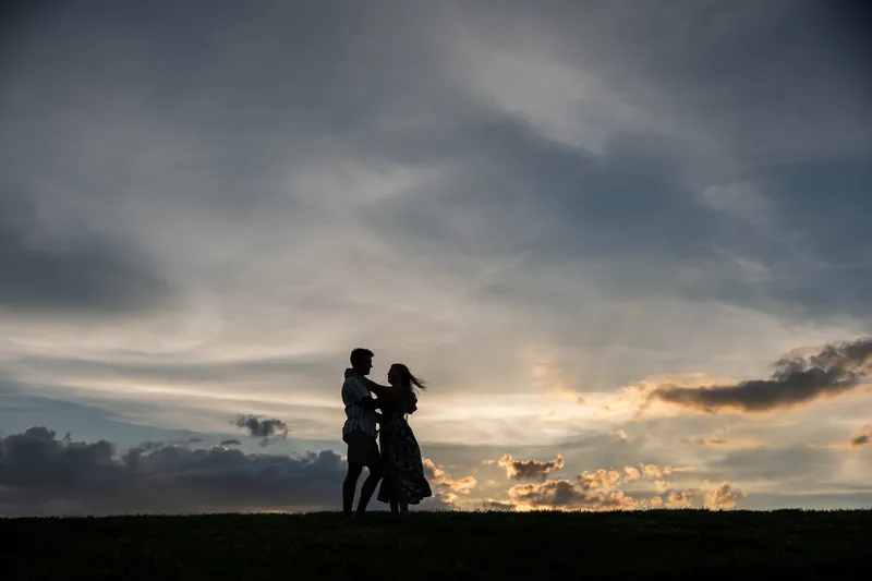 Silhouetted against a dramatic cloudy sunset, Abby and Gage stand together on the grounds of Castillo de San Marcos.