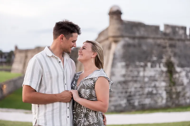 Gage in a striped shirt and Abby in a patterned sleeveless dress face each other with the fort's stone walls behind them.