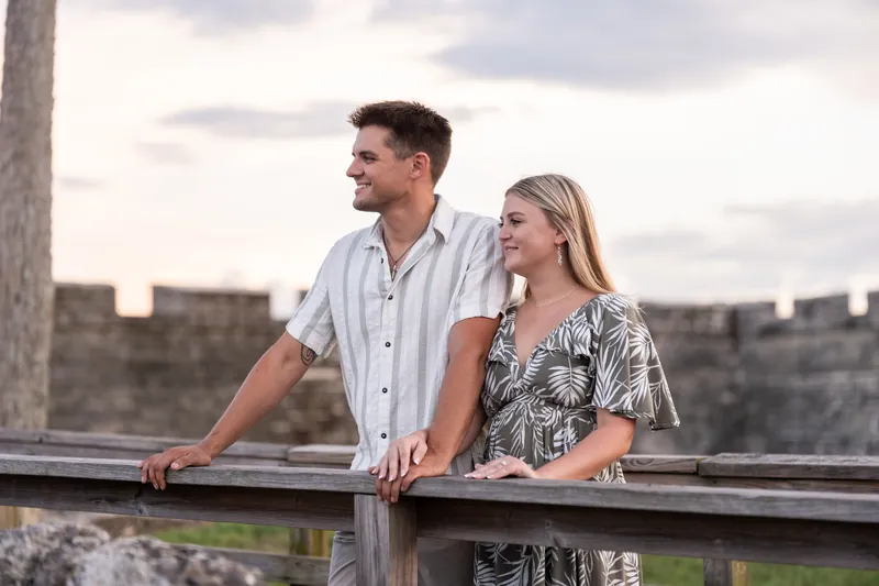 At a wooden railing overlooking the fort's grounds, Gage and Abby stand side by side against the fortress walls.