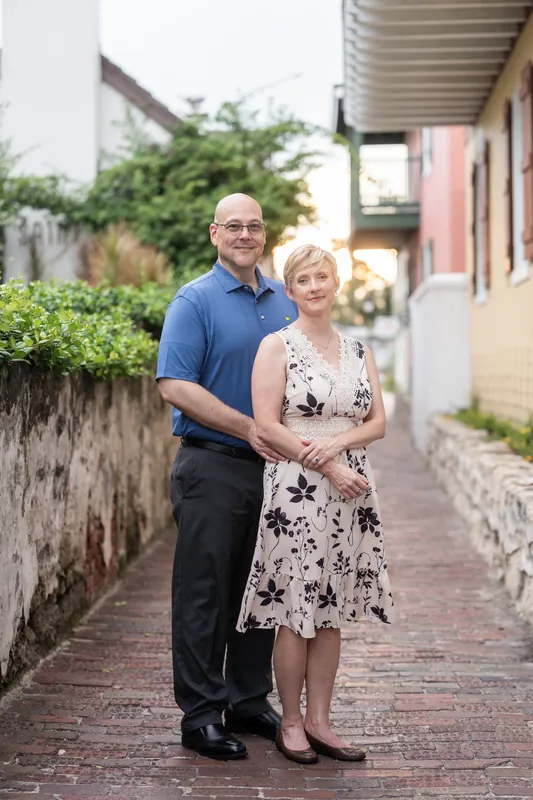 The couple walks hand-in-hand down a brick street lined with ivy-covered walls and historic buildings in Downtown St. Augustine.