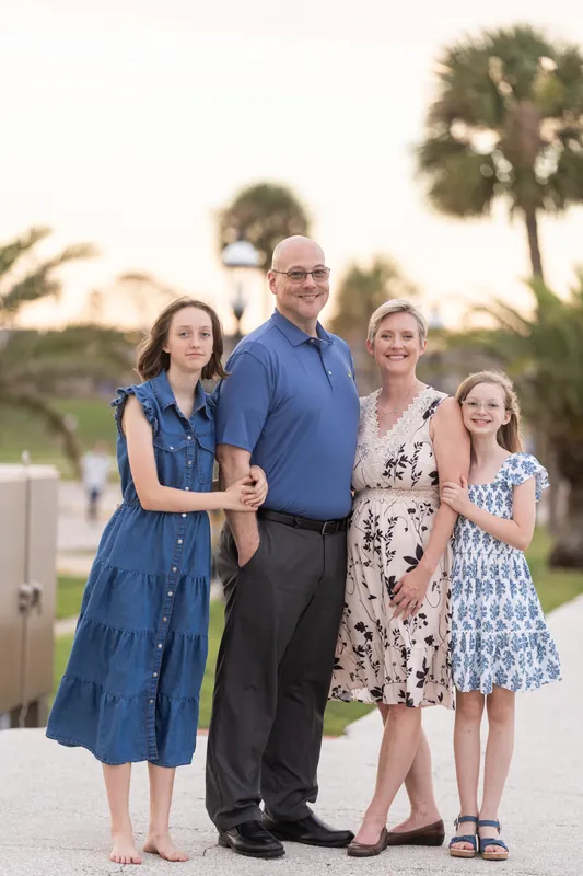 A group of five people stands together on a Downtown St Augustine promenade with palm trees and historic architecture glowing in background light.