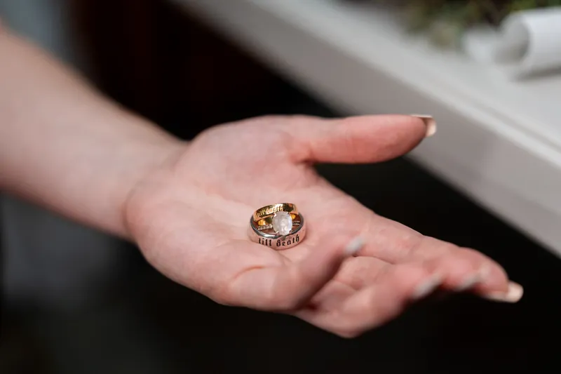 Woman's open palm displaying gold signet ring with dark stone and detailed band design.