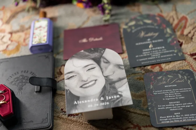 Alexandra & Jason's wedding invitation suite spread across patterned fabric with photo card, burgundy and black stationery pieces.