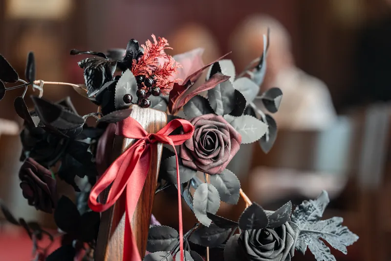 Dark roses with dusty miller and a coral ribbon cascade in an elegant bridal bouquet.