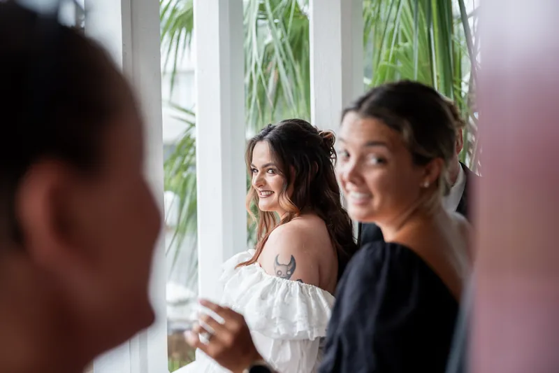 Alexandra smiles at Jason while standing by a window with greenery visible behind them.