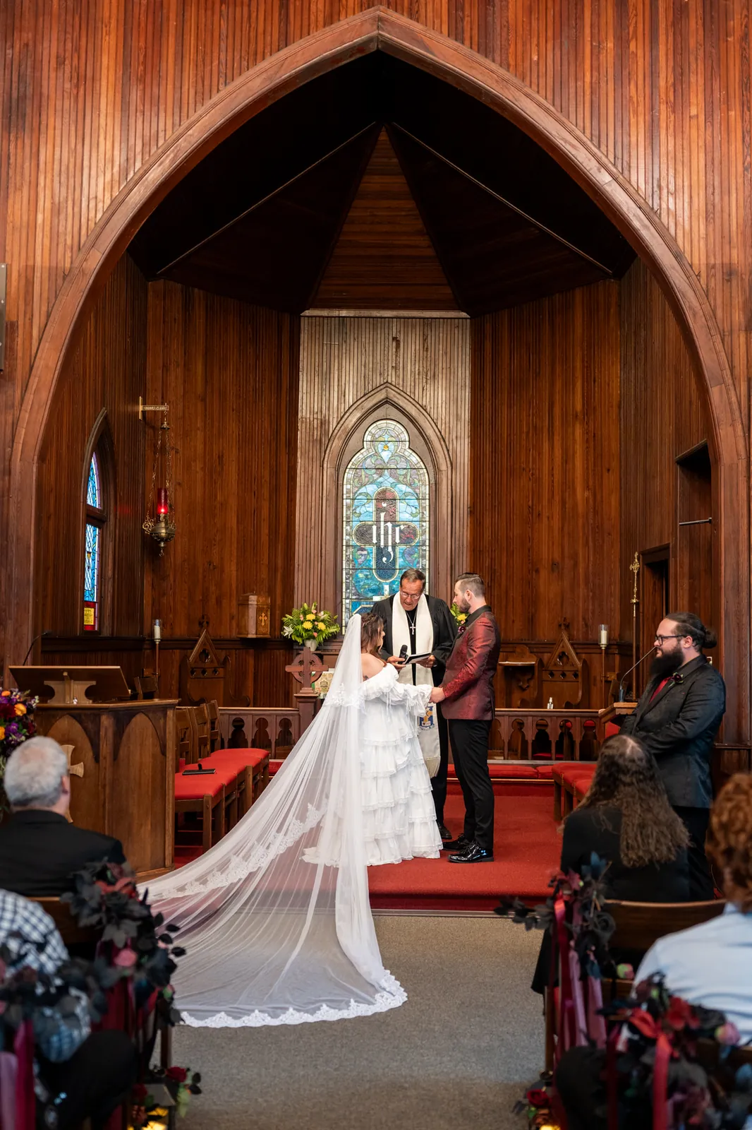 Alexandra's long veil trails behind her as she and Jason stand together at the altar during their ceremony.
