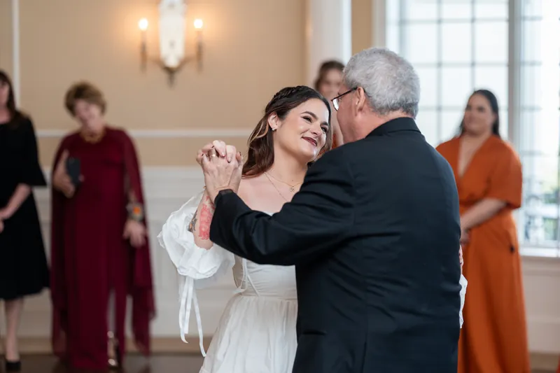 Alexandra dances with her father at Riverhouse Events while guests watch from the elegant, light-filled reception space.