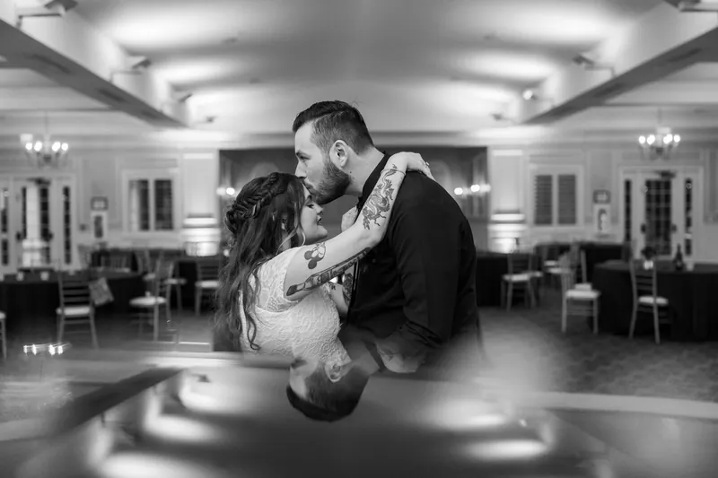 Jason dips Alexandra during their first dance in an elegant ballroom with coffered ceilings.