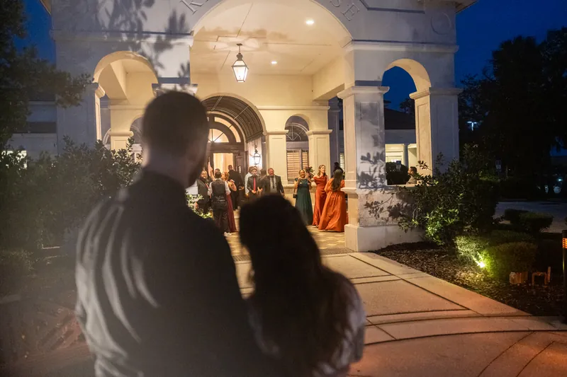 Guests gather on the grounds at Riverhouse Events as the venue glows warmly at dusk.