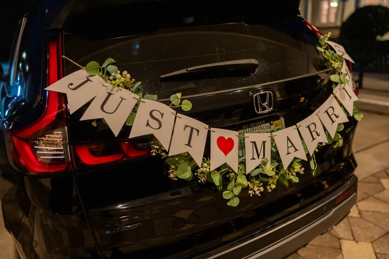 A black sedan displays a "JUST MARRIED" banner with greenery and a red heart detail.