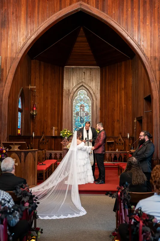 Alexandra's long veil trails behind her as she and Jason stand together at the altar during their ceremony.
