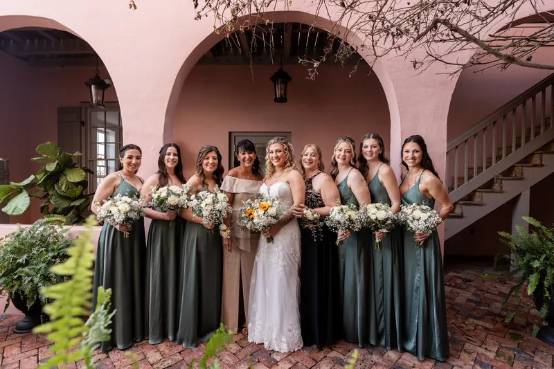 Bride with bridal party in sage dresses and mother in The White Room pink courtyard