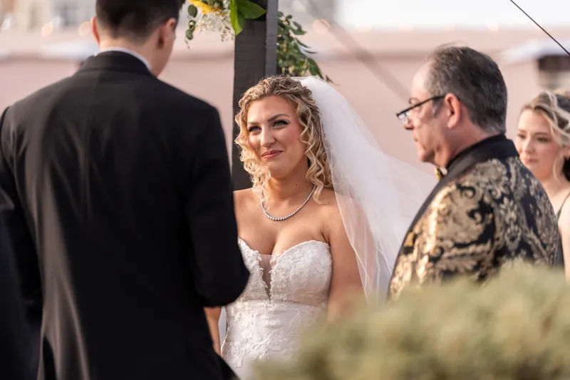 Bride smiling at groom during ceremony vow exchange on The White Room rooftop