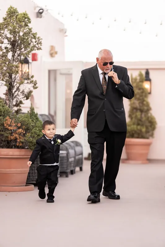 A groomsman escorts a young child down the aisle while guests look on at The White Room.