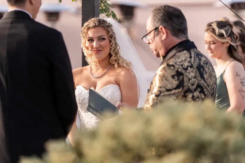 Alexis listens intently during the ceremony, wearing a strapless white gown and pearl necklace beside her father.