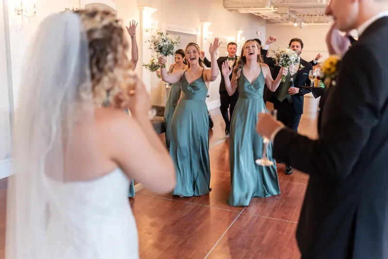 Alexis watches from the dance floor as bridesmaids in sage-blue dresses celebrate during the reception.