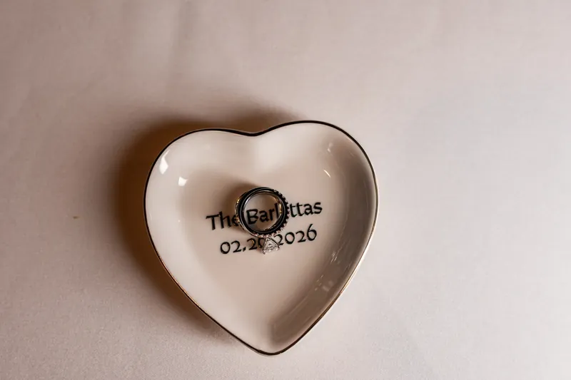 A white heart-shaped dish printed with "The Garbittas 02.17.2026" sits on a neutral surface.