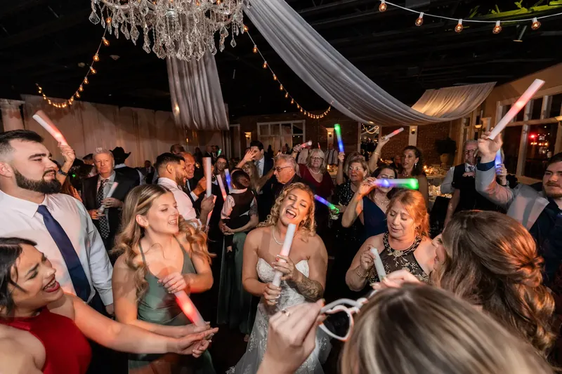 Guests dance and celebrate under string lights and a crystal chandelier at the reception.