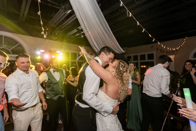 Dino holds Alexis close as they dance together while guests watch from around the dance floor.