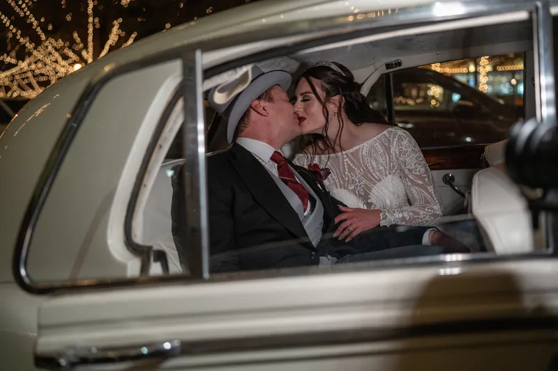 The couple shares a kiss inside a vintage car decorated for their departure from The Treasury on the Plaza.