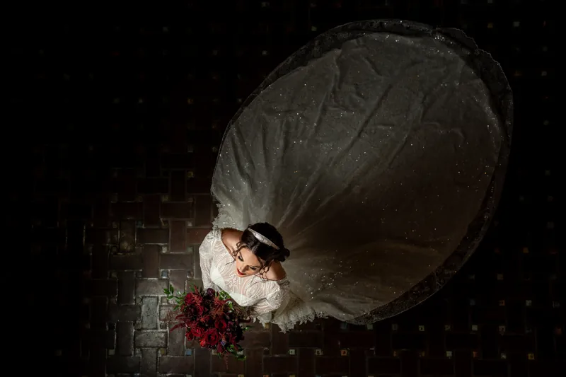 Overhead view of Alyson's ivory veil and burgundy bouquet arranged on a brick courtyard floor at night.