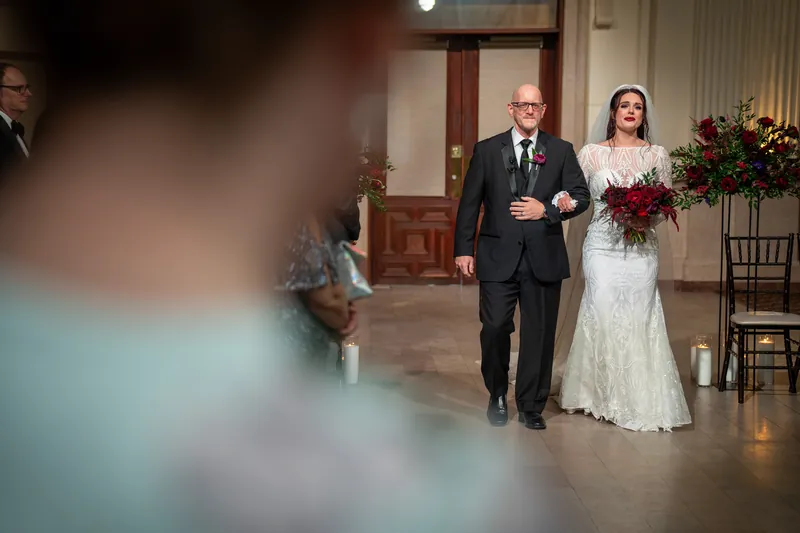 Alyson walks down the aisle escorted by her father in the grand hall at The Treasury on the Plaza.