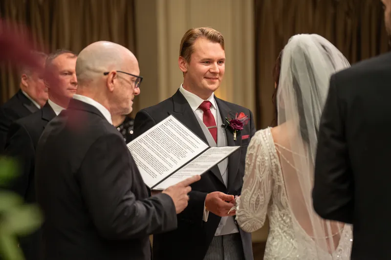 An officiant reads from a program while Sam and Alyson stand together during their ceremony at The Treasury on the Plaza.