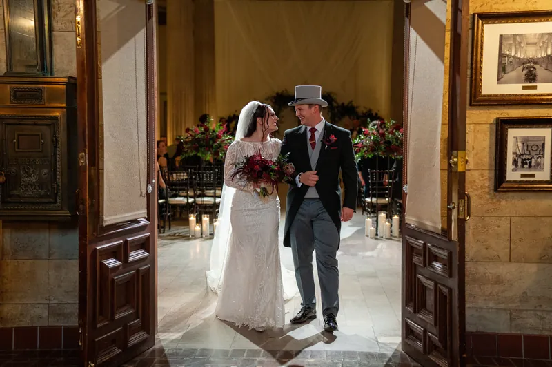 Alyson and Sam walk through ornate wooden doors after being pronounced married at The Treasury on the Plaza.