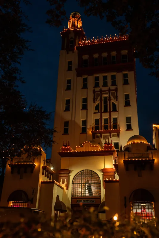 The Treasury's illuminated brick tower glows against the twilight sky, outlined with warm white string lights.