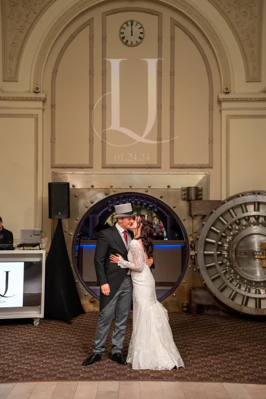 Alyson and Sam embrace under an arched doorway flanked by vintage clock decorations.