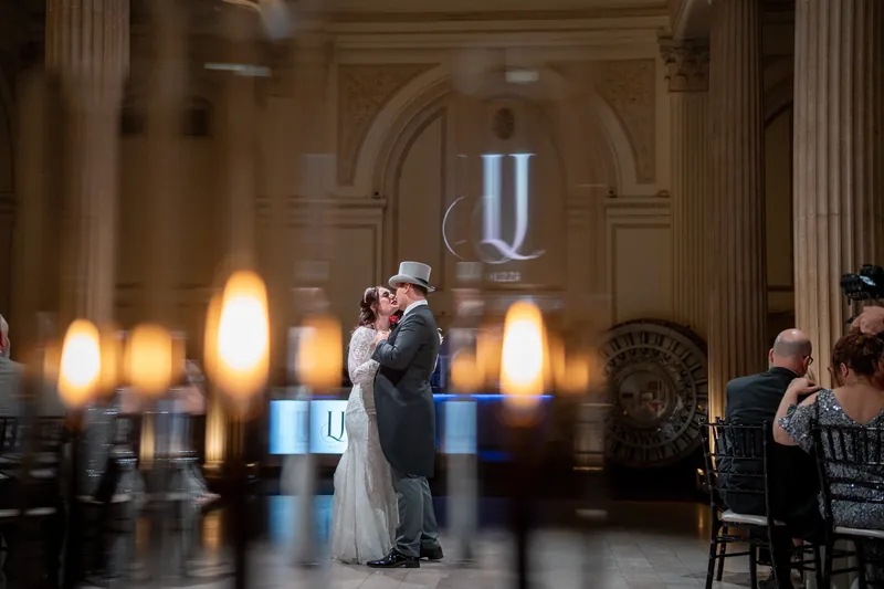 Alyson and Sam sway together during their first dance, surrounded by golden uplighting and candles.