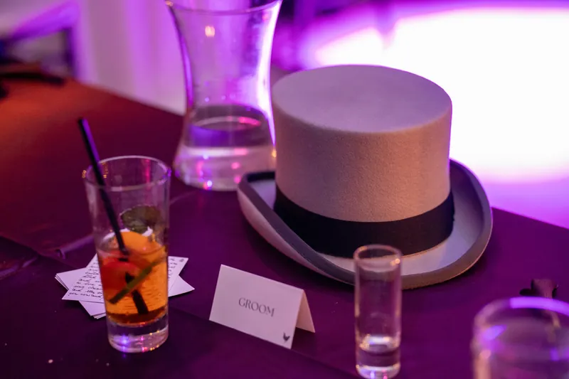 A white top hat and cocktail glass sit on a purple-lit table at The Treasury on the Plaza, St. Augustine.