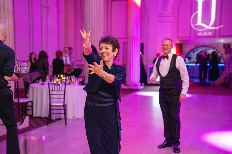 A guest dances with arms raised under purple lighting while guests watch from tables at The Treasury on the Plaza.