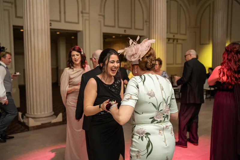 Two guests laugh together in the columned reception hall at The Treasury on the Plaza, St. Augustine.