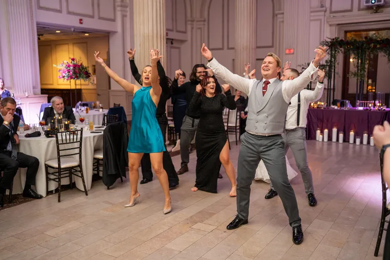 Guests jump and raise their arms on the dance floor at The Treasury on the Plaza during Alyson and Sam's reception.