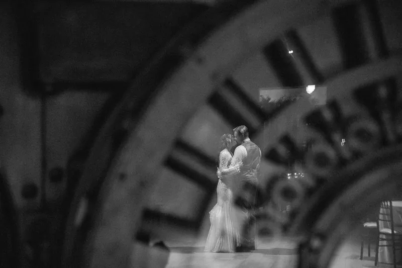 Soap bubbles drift past the couple in a soft-focus black-and-white moment at their indoor ceremony.